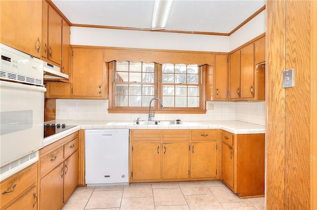 kitchen with tasteful backsplash, sink, light tile patterned floors, and white appliances