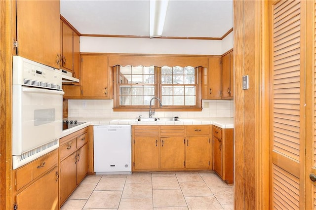 kitchen featuring tasteful backsplash, sink, white appliances, and light tile patterned flooring