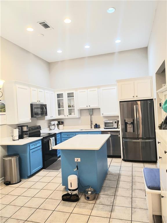 3473 Newtons Crest Cir, Snellville, GA 30078 - kitchen with appliances with stainless steel finishes, light countertops, a high ceiling, blue cabinets, and white cabinets