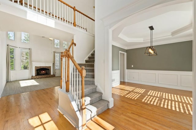 staircase featuring ornamental molding, a raised ceiling, a fireplace, and wood finished floors