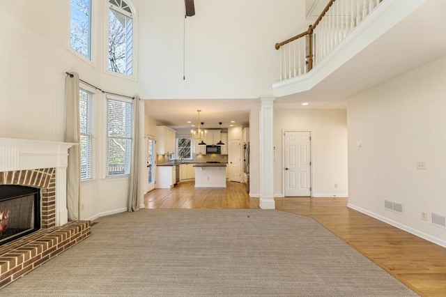 unfurnished living room featuring light wood-style floors, baseboards, a fireplace, and visible vents