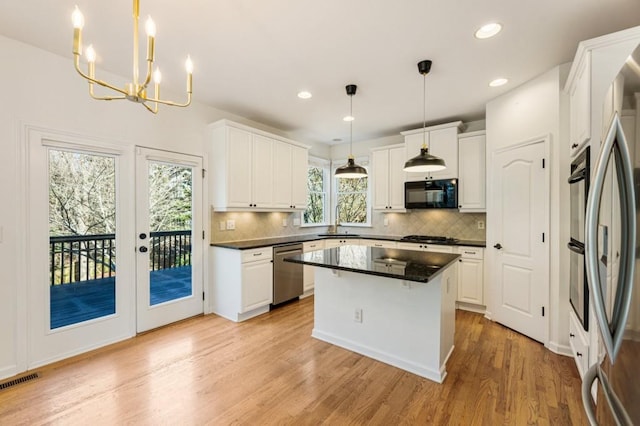 kitchen featuring white cabinetry, a kitchen island, appliances with stainless steel finishes, and decorative light fixtures