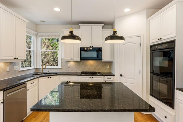 kitchen with black appliances, pendant lighting, a sink, and a center island