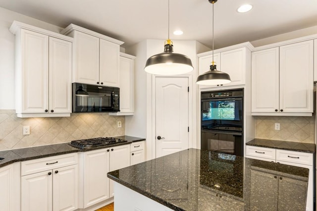 kitchen featuring dark stone counters, black appliances, hanging light fixtures, and white cabinetry