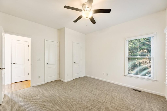 unfurnished bedroom featuring light carpet, baseboards, visible vents, and a ceiling fan