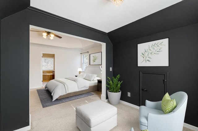 bedroom featuring connected bathroom, baseboards, a tray ceiling, and light colored carpet