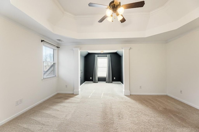 spare room featuring a tray ceiling, light colored carpet, crown molding, and visible vents