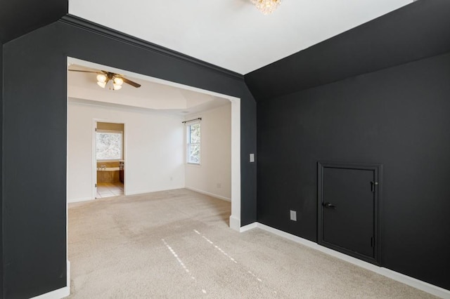 spare room featuring baseboards, ceiling fan, a tray ceiling, and light colored carpet