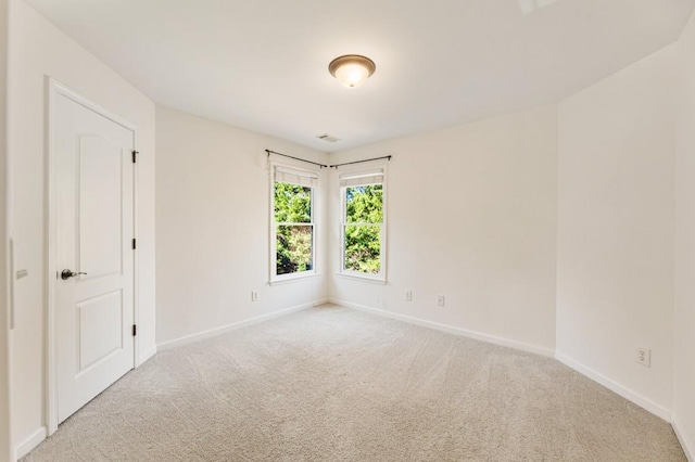 spare room featuring light carpet and baseboards