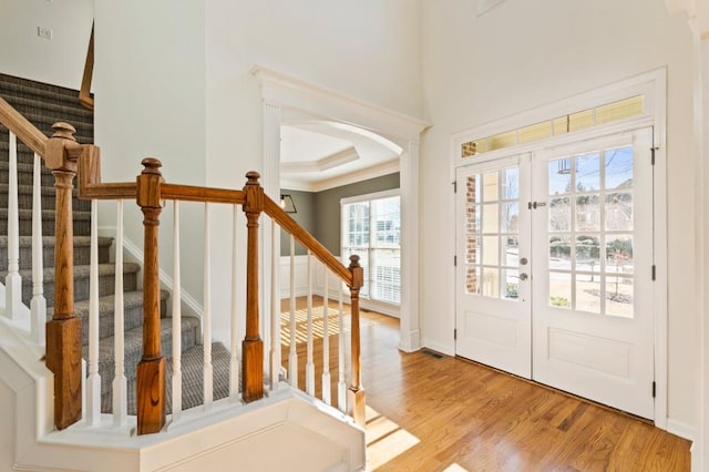 entrance foyer featuring stairs, arched walkways, wood finished floors, and french doors