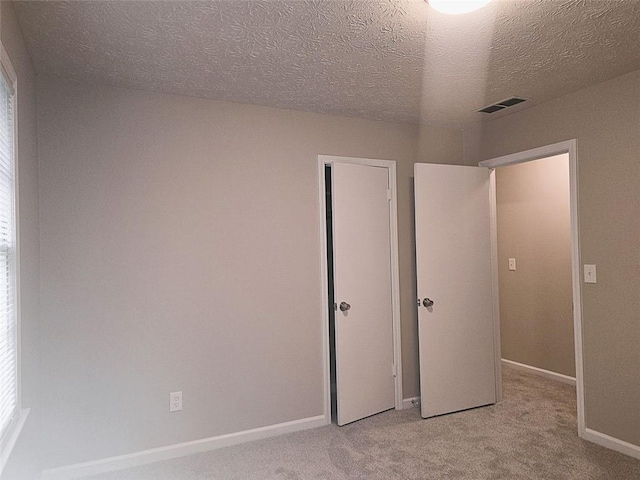 unfurnished bedroom featuring a textured ceiling and light carpet