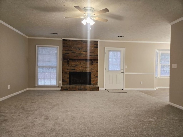 unfurnished living room featuring a textured ceiling, a wealth of natural light, a brick fireplace, light colored carpet, and crown molding