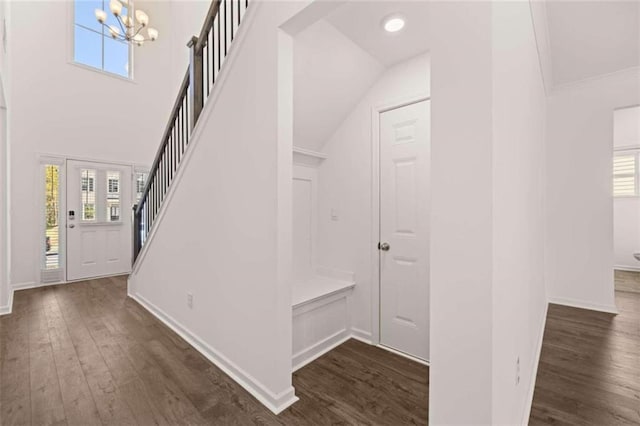 staircase featuring a notable chandelier, a healthy amount of sunlight, wood-type flooring, and vaulted ceiling