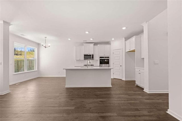 kitchen featuring an island with sink, white cabinetry, dark wood-type flooring, sink, and stainless steel appliances