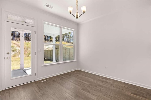 unfurnished dining area with a notable chandelier, a healthy amount of sunlight, dark wood-type flooring, and crown molding