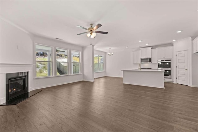 unfurnished living room featuring sink, ceiling fan with notable chandelier, and dark hardwood / wood-style flooring