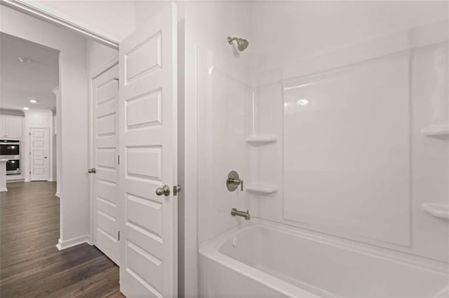 bathroom with hardwood / wood-style flooring and bathing tub / shower combination