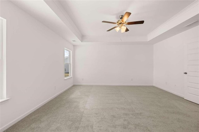 carpeted spare room with ceiling fan and a tray ceiling