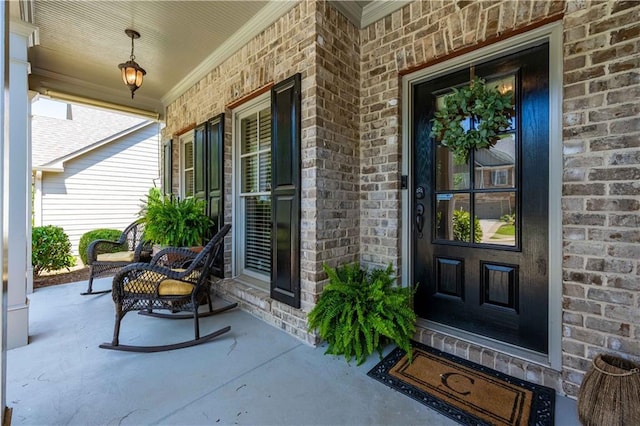 view of exterior entry featuring covered porch and brick siding