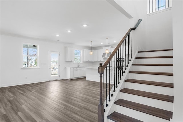 stairway featuring wood-type flooring, sink, and ornamental molding