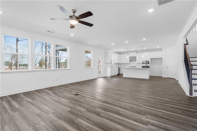 unfurnished living room featuring ceiling fan and dark hardwood / wood-style flooring