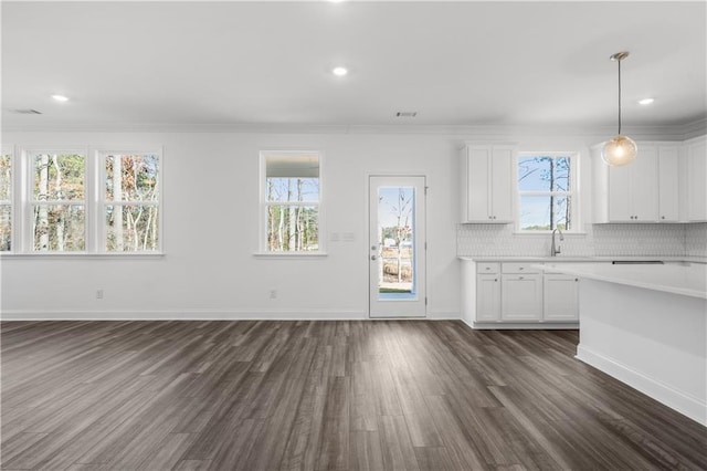 kitchen featuring dark wood-type flooring, crown molding, decorative light fixtures, white cabinets, and backsplash