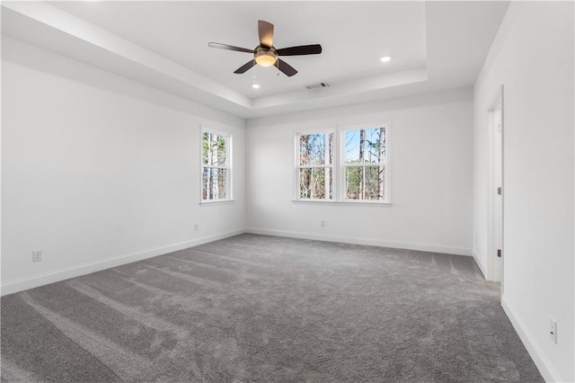 carpeted empty room with a tray ceiling and ceiling fan