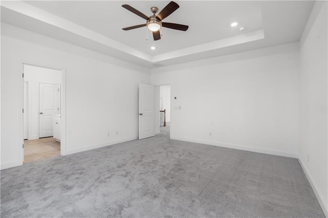 carpeted spare room featuring ceiling fan and a tray ceiling