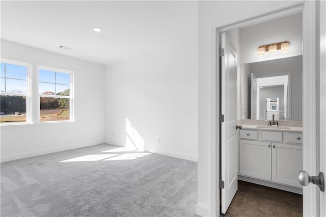 unfurnished bedroom featuring sink, dark carpet, and ensuite bathroom