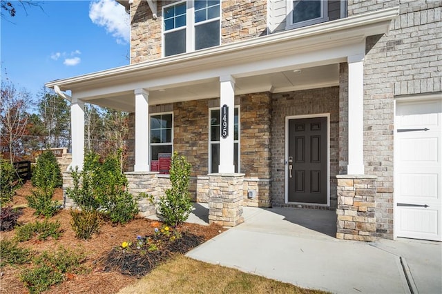 view of exterior entry featuring a garage and covered porch