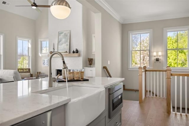 kitchen featuring visible vents, appliances with stainless steel finishes, open floor plan, light stone countertops, and a sink