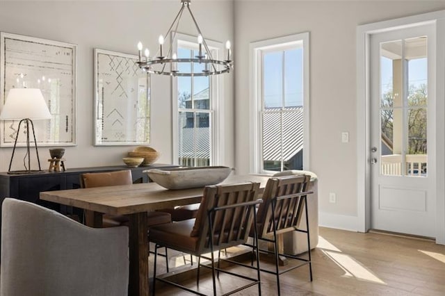 dining space featuring a chandelier, baseboards, and wood finished floors