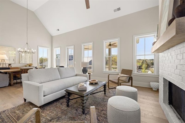 living room with ceiling fan with notable chandelier, a fireplace, and plenty of natural light