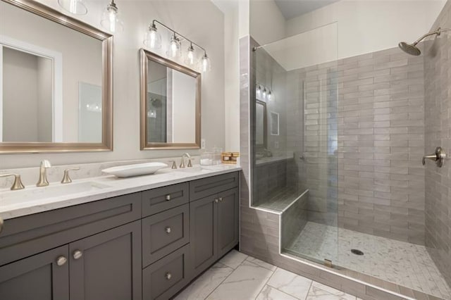 bathroom with a tile shower, marble finish floor, double vanity, and a sink