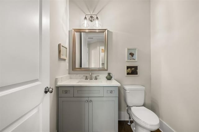 half bath featuring vanity, toilet, and baseboards