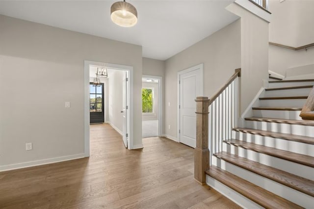 entrance foyer with stairway, wood finished floors, and baseboards