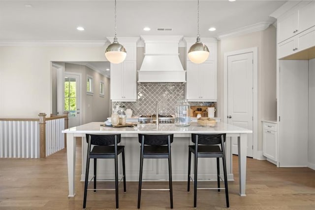 kitchen featuring light wood-type flooring, white cabinetry, and custom exhaust hood