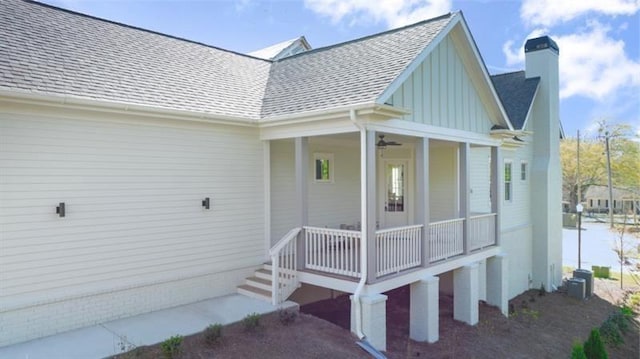 view of exterior entry featuring covered porch, roof with shingles, and a chimney