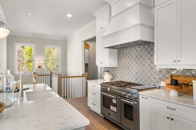 kitchen featuring range with two ovens, premium range hood, wood finished floors, a sink, and ornamental molding