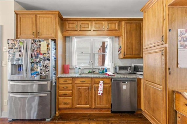 kitchen featuring light stone counters, sink, stainless steel appliances, and dark wood-type flooring