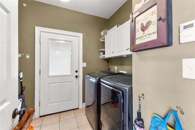 clothes washing area with cabinets, separate washer and dryer, and light tile patterned floors