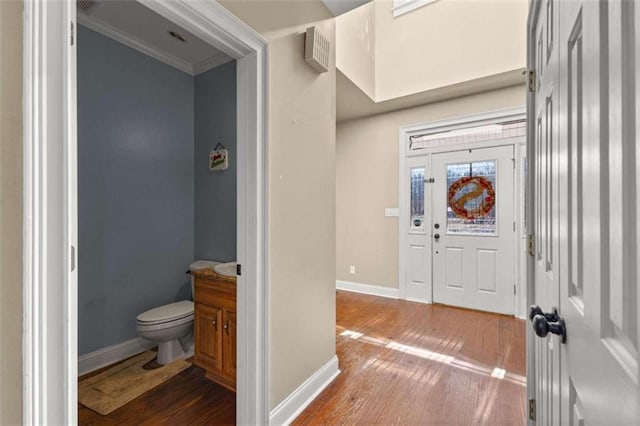 foyer entrance with dark wood-type flooring and crown molding