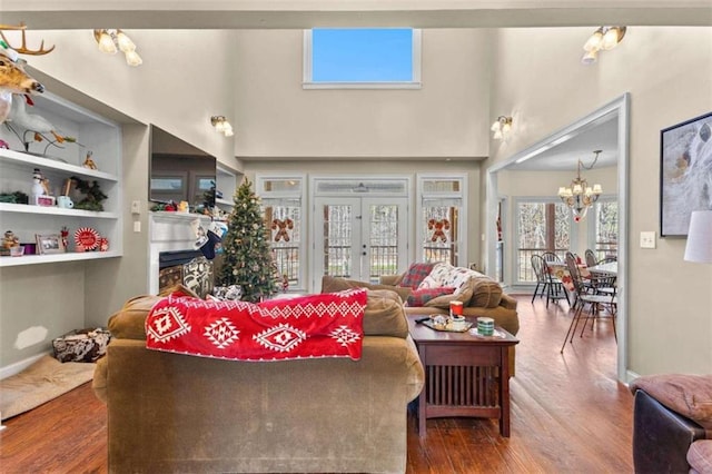 living room with an inviting chandelier, hardwood / wood-style floors, french doors, and built in shelves