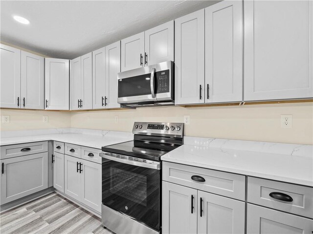 239 Brown Dr, Clermont, GA 30527 - kitchen with stainless steel appliances, light stone countertops, gray cabinetry, and light wood-style flooring