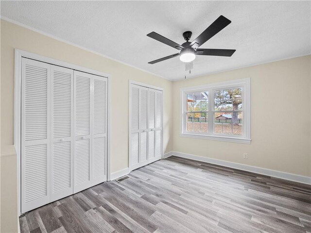 239 Brown Dr, Clermont, GA 30527 - unfurnished bedroom with baseboards, a ceiling fan, multiple closets, and wood finished floors
