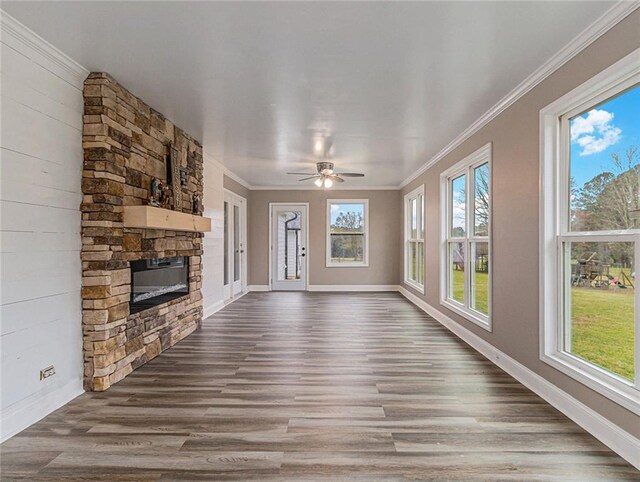 unfurnished living room with crown molding, dark wood finished floors, a wealth of natural light, and a fireplace