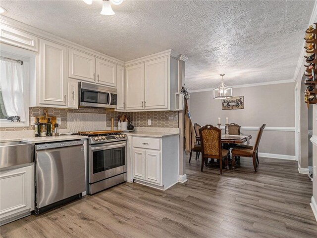 kitchen with an inviting chandelier, wood finished floors, backsplash, and stainless steel appliances