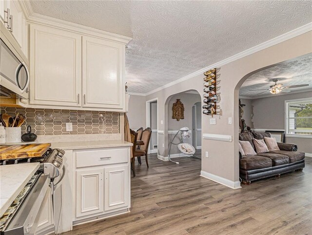 kitchen with arched walkways, light wood finished floors, ceiling fan, and stainless steel appliances