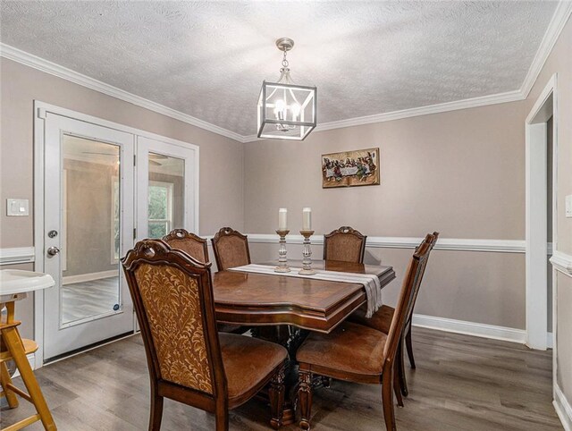 dining area with french doors, a textured ceiling, crown molding, wood finished floors, and a chandelier
