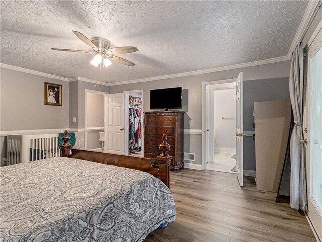 bedroom featuring a textured ceiling, baseboards, wood finished floors, a spacious closet, and visible vents